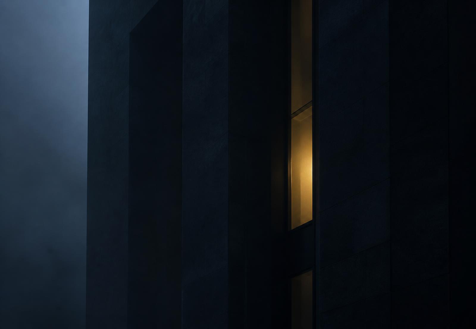 Modernist stone facade at dusk with a single lit window